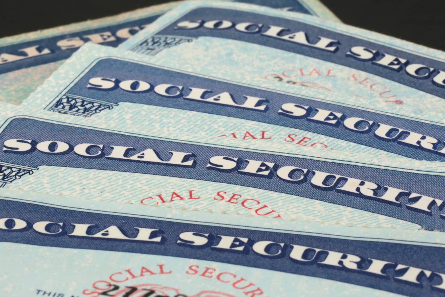 Close-up of five Social Security cards laid out on top of each other.
