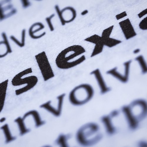 Close-up of the word "dyslexia" in bold print from a dictionary, with surrounding text slightly blurred.