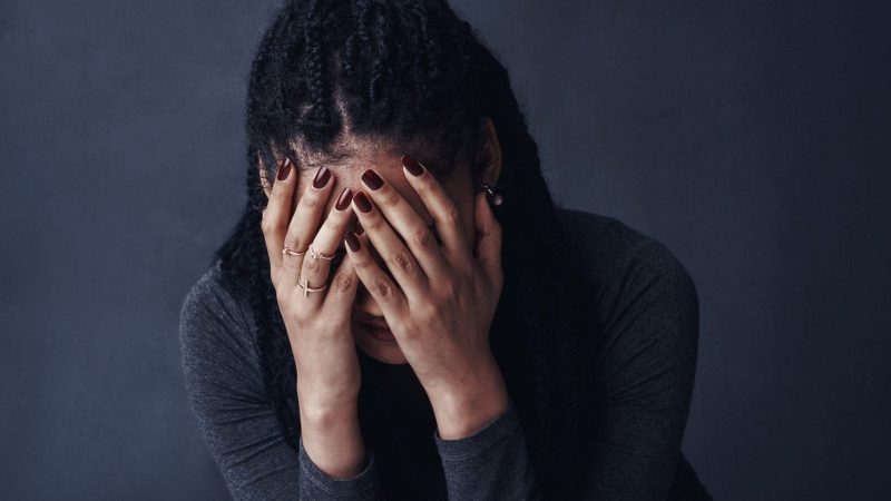 A woman covering her face with her hands, appearing distressed.