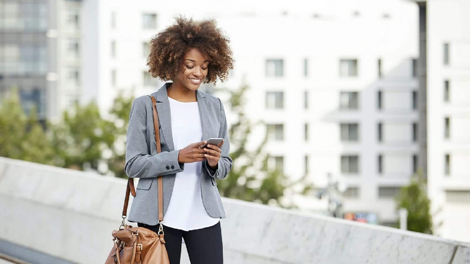 Young Woman Using Her Mobile Phone While Walking Stock Photo