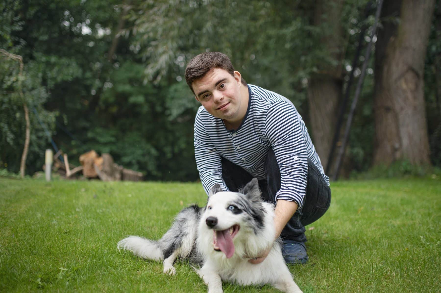 A young man with special needs petting his dog.