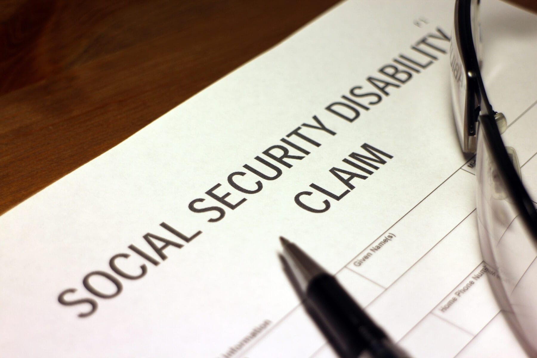 A Social Security Disability Claim form with a pen and a pair of glasses.
