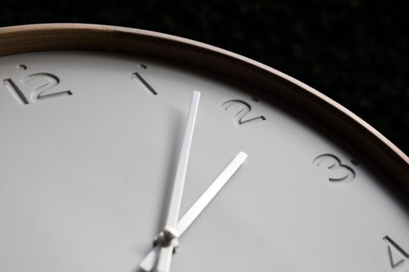 A close-up of a minimalistic clock with silver hands.