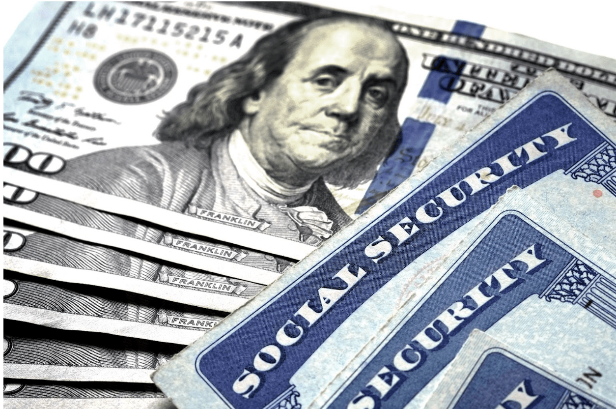 Three Social Security cards on top of six $100 bills