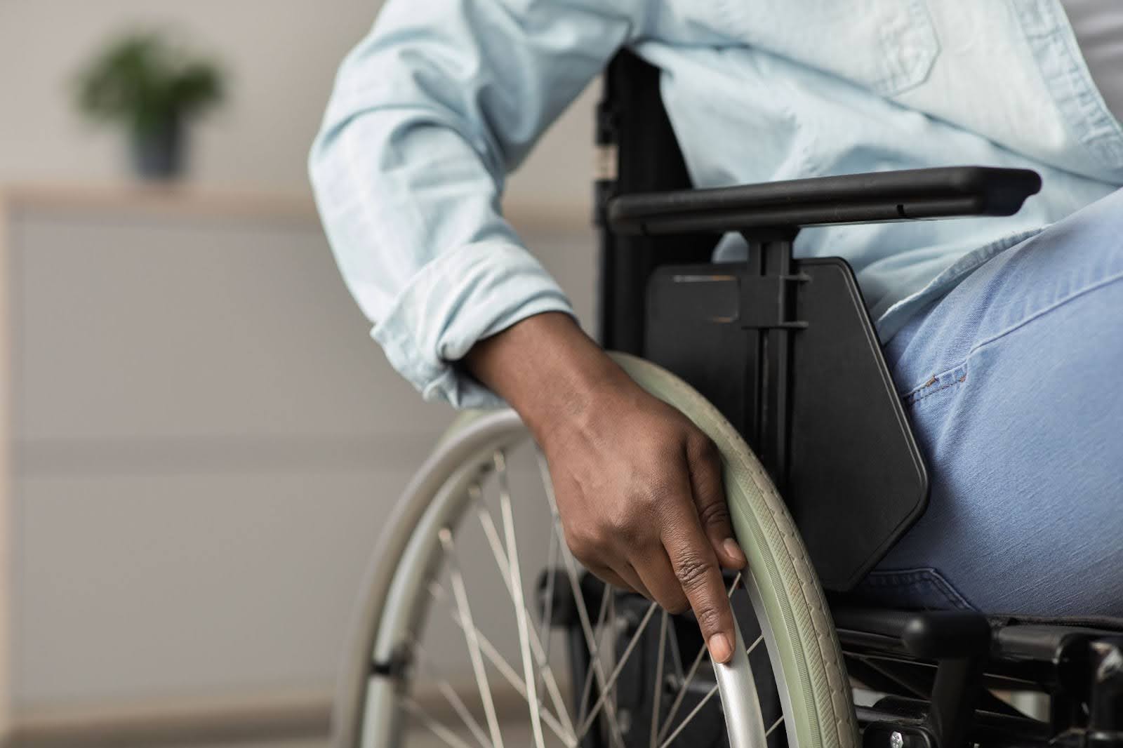 Close-up of a man with his hand on the wheel of his wheelchair.